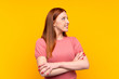 © luismolinero - Young redhead woman over isolated yellow background looking to the side
