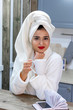 © September - Beautiful girl after shower in a towel and bathrobe enjoys coffee on the kitchen