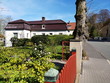 Roter Zaun mit grünem Garten im Frühling bei blauem Himmel und Sonnenschein an der Detmolder Straße in Oerlinghausen bei Bielefeld am Hermannsweg im Teutoburger Wald in Ostwestfalen-Lippe
