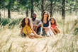 © Inti St. Clair - Portrait of happy mixed race family sitting in grass in park in summer