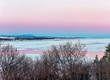 Pink sunset sky over a pink frozen river with a boat in Quebec