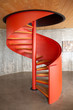 Red circular staircase between a concrete floor and a wooden ceiling