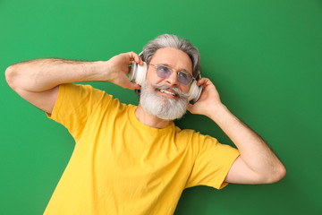 Sticker - Happy elderly man listening to music on color background