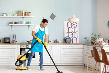 Sticker - Young man hoovering floor in kitchen