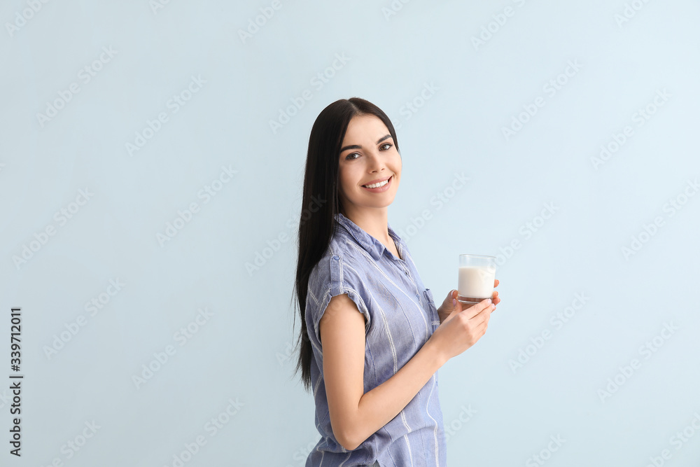 Beautiful young woman with milk on color background