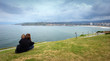 © Julen - Gijon, Asturias. Spain. Two lovers enjoy the views of the sea on top of a park on a cloudy day in Gijon, Spain.