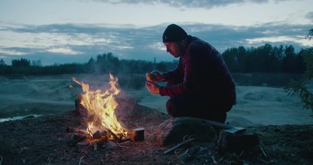 Wall Mural - a man is drinking hot tea in nature, campfire, camping, night