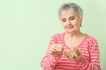 Sticker - Elderly woman suffering from mental disability with cubes on color background