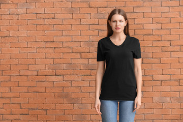 Wall Mural - Young woman in stylish t-shirt on brick background