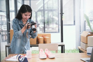 Beautiful young asian business owner working with computer and tablet standing in workshop.Responding on business e-mail,writing the order of product customer orders.