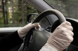 © canberk - Man wearing surgical gloves holding steering wheel