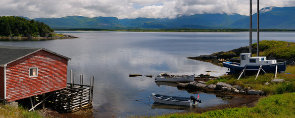 Panorama of boathouse and boats at St Pauls Inlet Newfoundland with Gros Morne Long Range Mountains