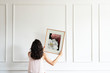 © rawpixel.com - Woman hanging a frame on a white wall