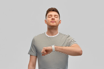 Wall Mural - technology, relax and people concept - calm young man with smart watch meditating over grey background