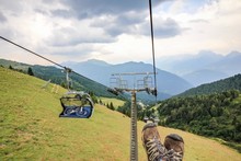 Low Section Of Person On Ski Lift Over Landscape Against Sky