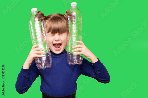 Little girl holding plastic bottles with close eyes and screams for help in protecting our planet from excessive use of plastic isolated on green