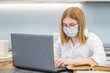 © Ermolaev Alexandr - Teen girl wearing medical mask is engaged in distance learning with a laptop. Quarantine and coronavirus epidemic concept