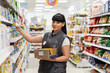 © _KUBE_ - A portrait of young pretty Caucasian woman, an employee of a supermarket, is engaged in putting goods on display. Concept of business, shopping and work