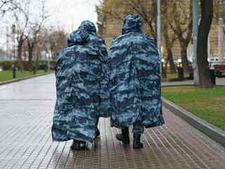 People in special protective suits on the Moscow city street. Back / rear view. Coronavirus pandemic lifestyles.