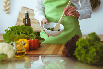 Unknown human hands cooking in kitchen. Woman is busy with vegetable salad. Healthy meal, and vegetarian food concept