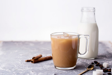 Wall Mural - Cooled coffee with milk, cinnamon sticks, coffee beans, sugar, spoon on the table.