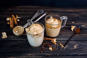 Wall Mural - Delicious and fragrant dalgona coffee in glass cups, cinnamon sticks, dried mushrooms, a spoon of instant coffee, sugar.