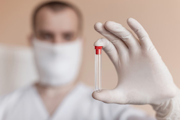 Wall Mural - Doctor in protection face mask against coronavirus holds an empty test tube in hands. Close-up.