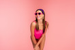 © LIGHTFIELD STUDIOS - Woman in sunglasses smiling and leaning forward isolated on pink