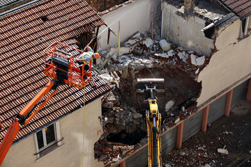 Démolition d'une habitation par un engin de chantier.