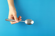 © ltyuan - Top view woman hand holding spoon on blue background