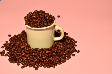 Shot of a pink cup with coffee beans on pink background