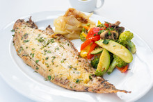Sole Meunière Fish With Grilled Vegetables And Caramelized Onions On A White Plate With White Background. LENGUADO MENIER