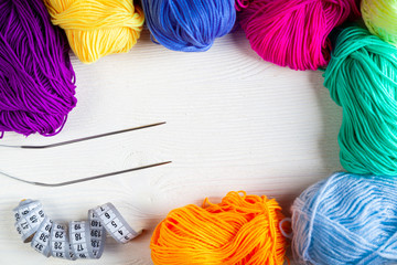 Balls of colored yarn on a white wooden background. Top view.