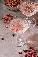 Wall Mural - Crystal vintage glasses of pink rose champagne, cider or lemonade with dry rose buds. Grey texture background.