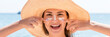 Beautiful young woman in hat is applying sunblock under her eyes and on her nose like Indian. Sun protection concept