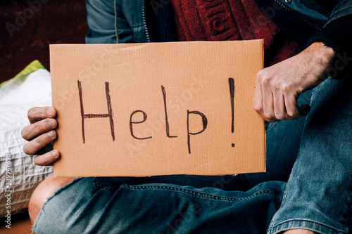 Fotomural A homeless person holds a sign , asks for work, and seeks help