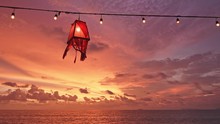 Red Lantern Beach Light With Lightbulbs Are Hanging On Wired Line Above Beach And Sea At Ko Lanta Island, Thailand. Breathtaking Sunset With Vibrant And Magic Colors In Background.