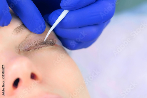 Cosmetologist bending lashes with needle into curlers, lift eyelashes laminaton procedure in beauty salon for woman, closeup eye. Beautician making lash lifting in cosmetology clinic, hands closeup.