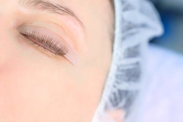 Woman's closed eye with bending lashes on curlers, lift eyelashes laminaton, closeup view. Making lash lifting in cosmetology clinic for young girl.