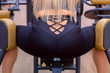 Sporty woman on personal training making exercise for legs and booty on training machine in gym, back view, booty closeup. Fitness and sport concept. Blonde girl training in gym, workout.