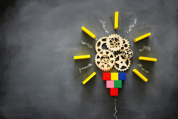 Wall Mural - Education concept image. Creative idea and innovation. Wooden gears light bulb metaphor over blackboard