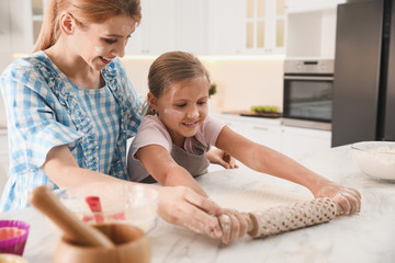 Wall Mural - Mother and daughter rolling dough together in kitchen