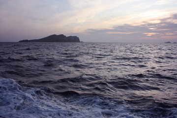 Wall Mural - romantic blue sunset between the waves of the Mediterranean sea and the islets of Ibiza on the horizon