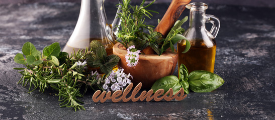 Wall Mural - Homegrown and aromatic herbs on rustic background with rosemary and basil and wellness letters made of wood