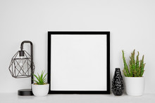 Mock Up Black Square Frame With Home Decor And Potted Plants. White Shelf And Wall. Copy Space.