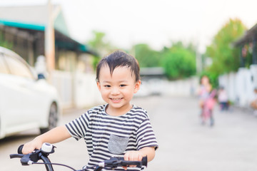 Wall Mural - 3 years old happy toddler asian boy child ride bike in street at home village .boy ride bicycle to play at playground : Healthy happy funny smiling face young adorable lovely boy child kid at home.