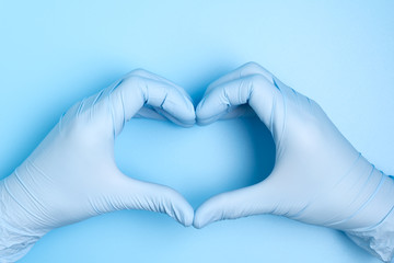 blue hand gloves making heart shape on blue background for care, love or support medical team