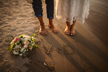 Wall Mural - The bride's and the groom's feet in the sand on the beach