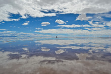 Salt Mountains In Uyuni Salt Flat (Bolivia), The Biggest Salar In The World Covered With Water And Reflecting Like A Mirror The Sky During A Bright Day With Blue Sky And White Clouds.