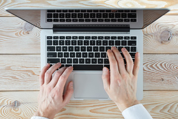 Fototapete - Top view of man's hands typing on laptop in sunny day. Coworking or working at home concept image.